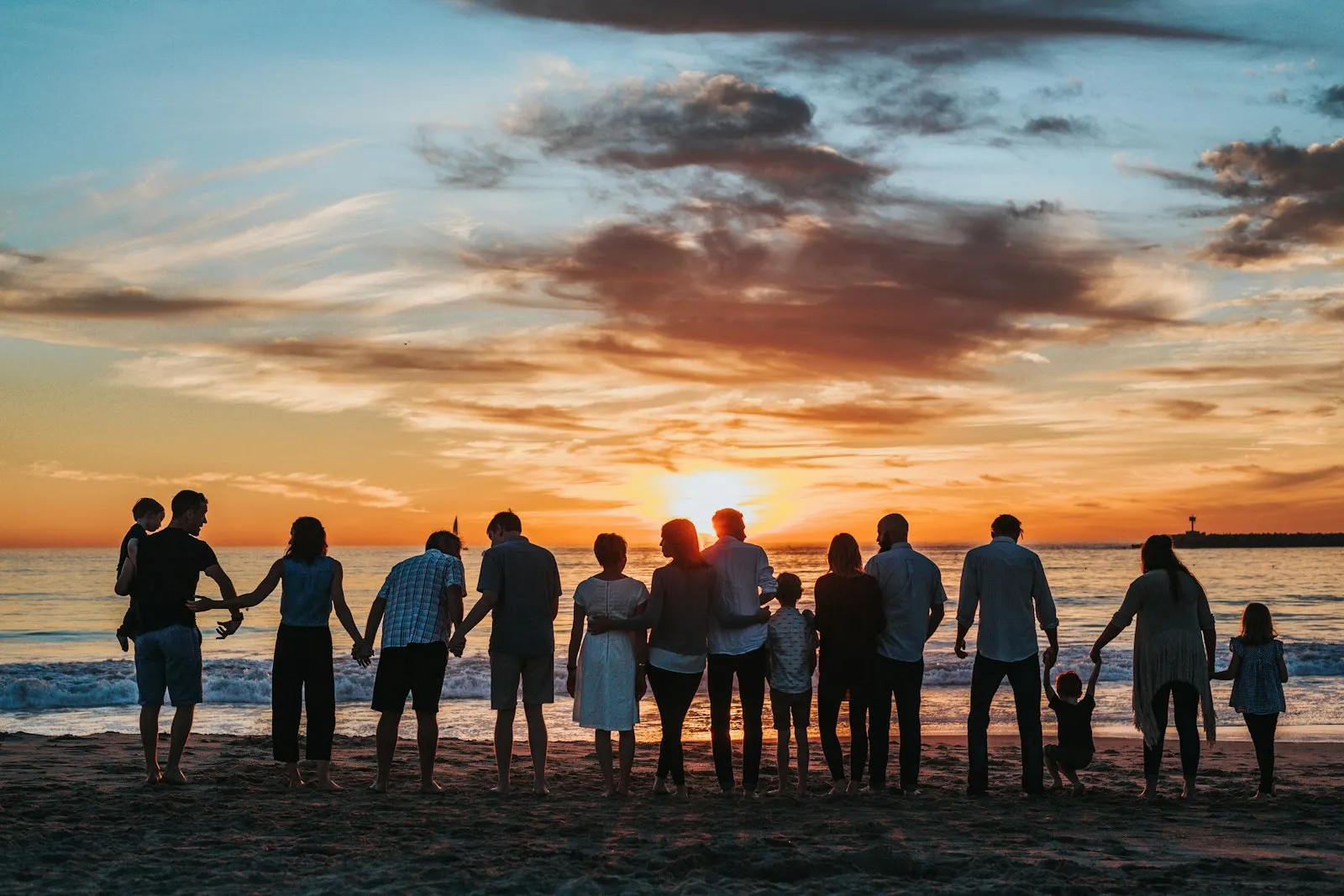 A family standing together at the water's edge in warm sunset light